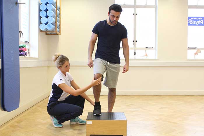 Customer guided through leg treatment by instructor in Manchester Physio Clinic