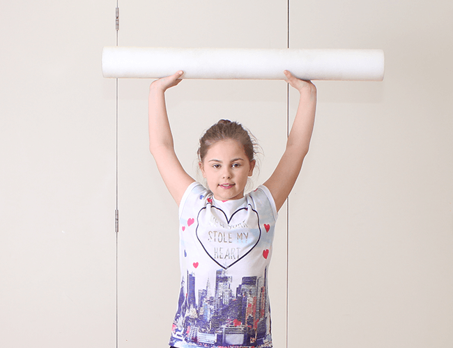 Young child recieves physiotherapy treatment using foam rollers during session.