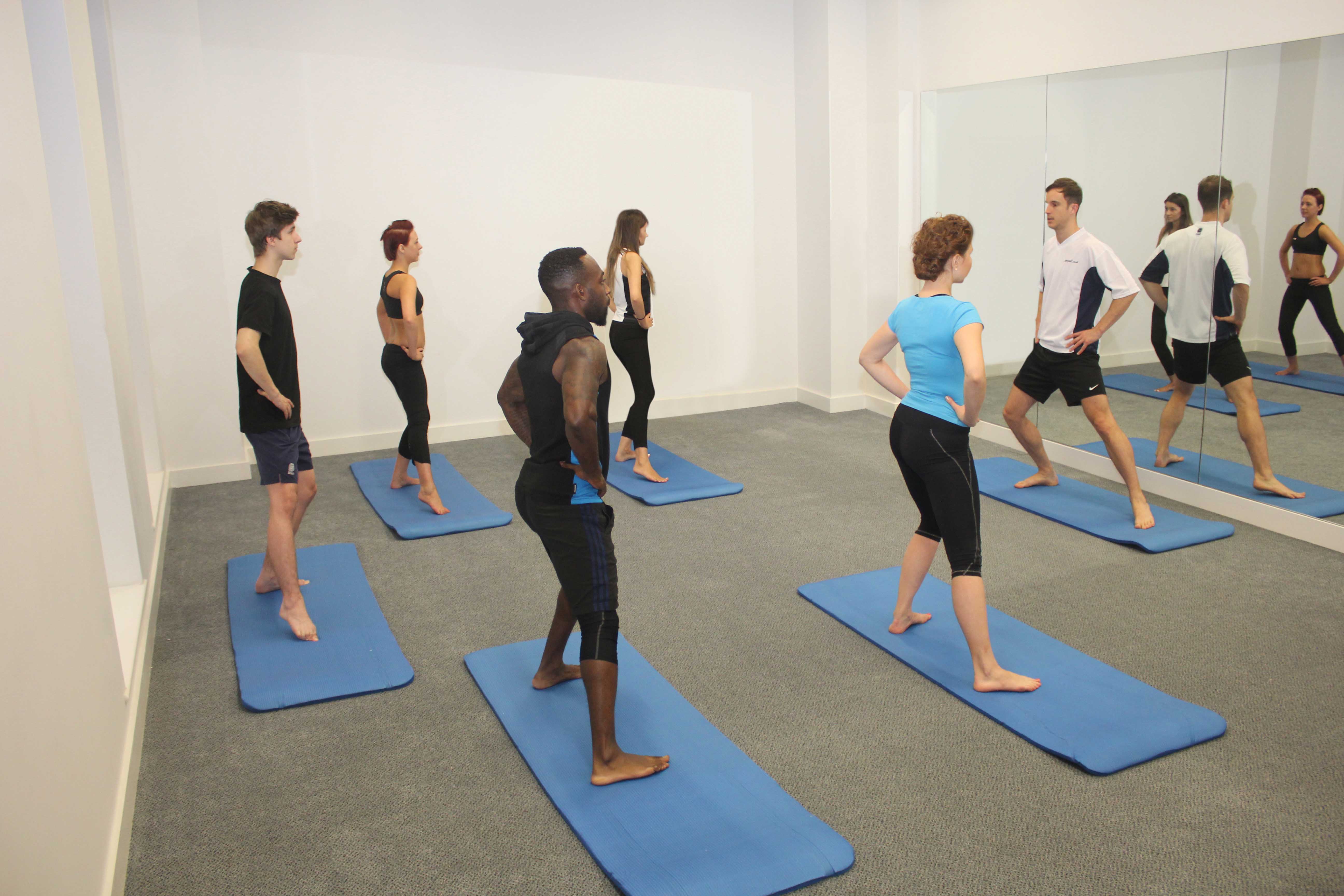 Physiotherapist led pilates class using foam rolls 