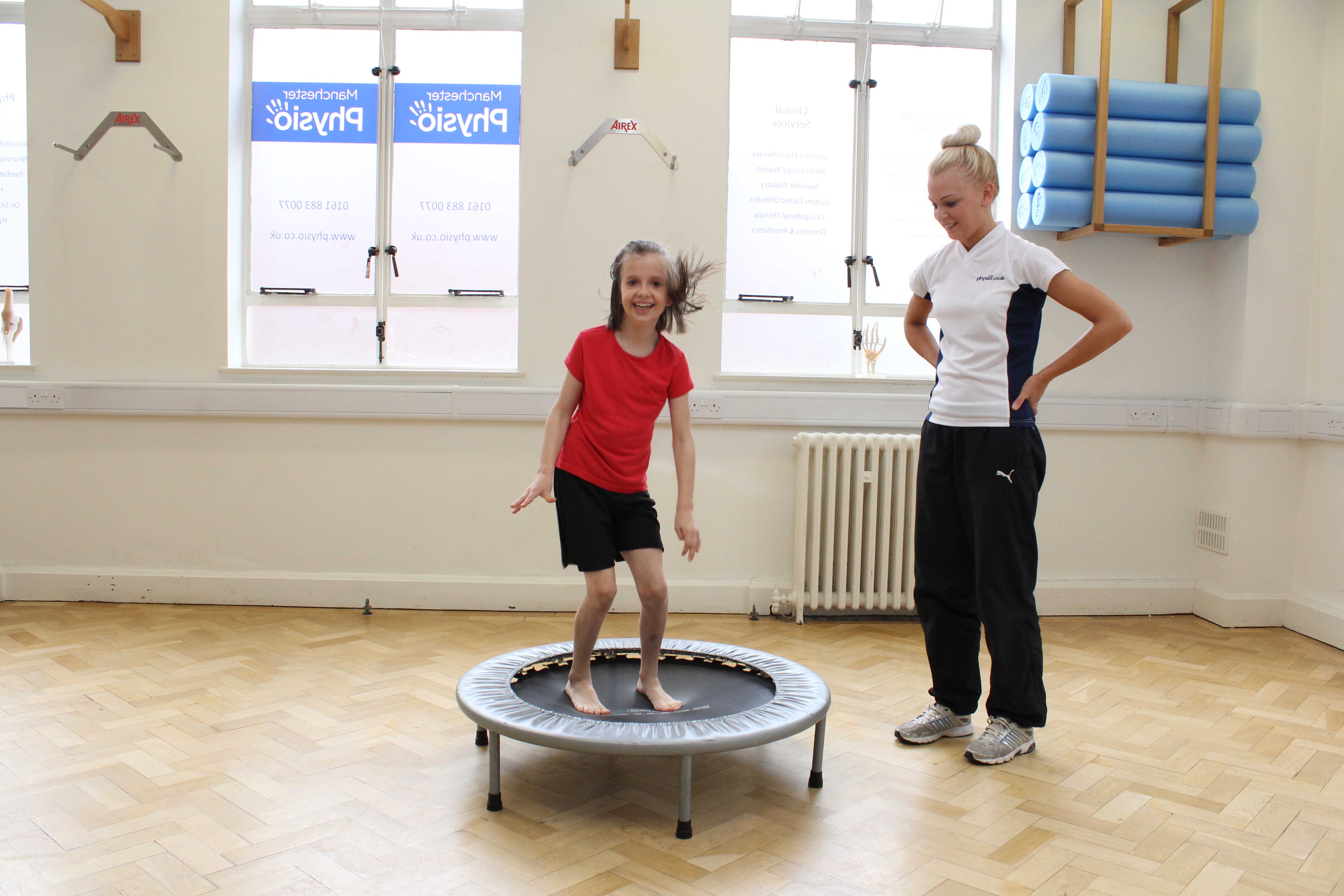 Paediatric physiotherapist supervising mobility exercises on the trampette