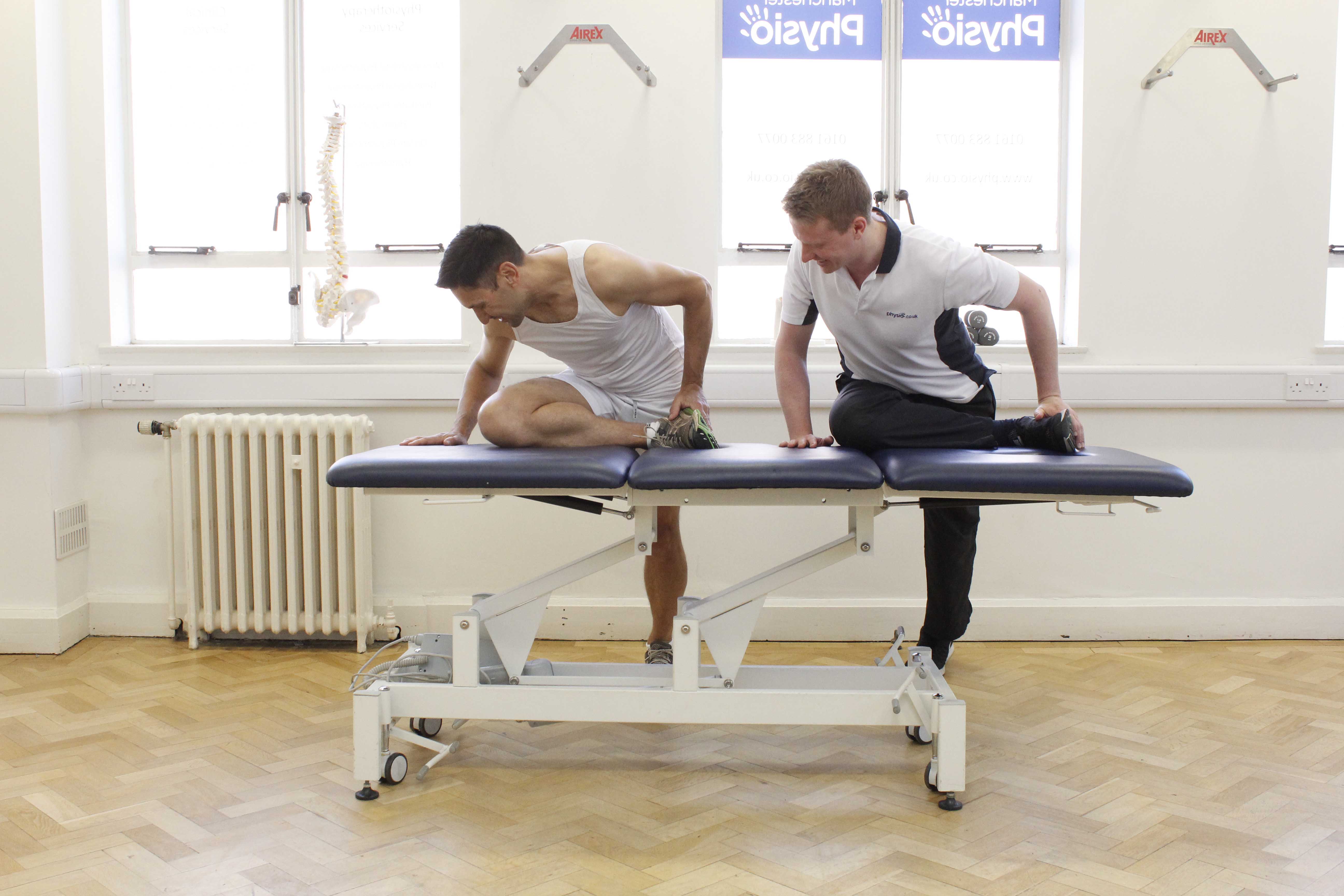 Specialist physiotherapist guiding client through hip and knee stretches for runners Specialist physiotherapist guiding client through hip and knee stretches for runners