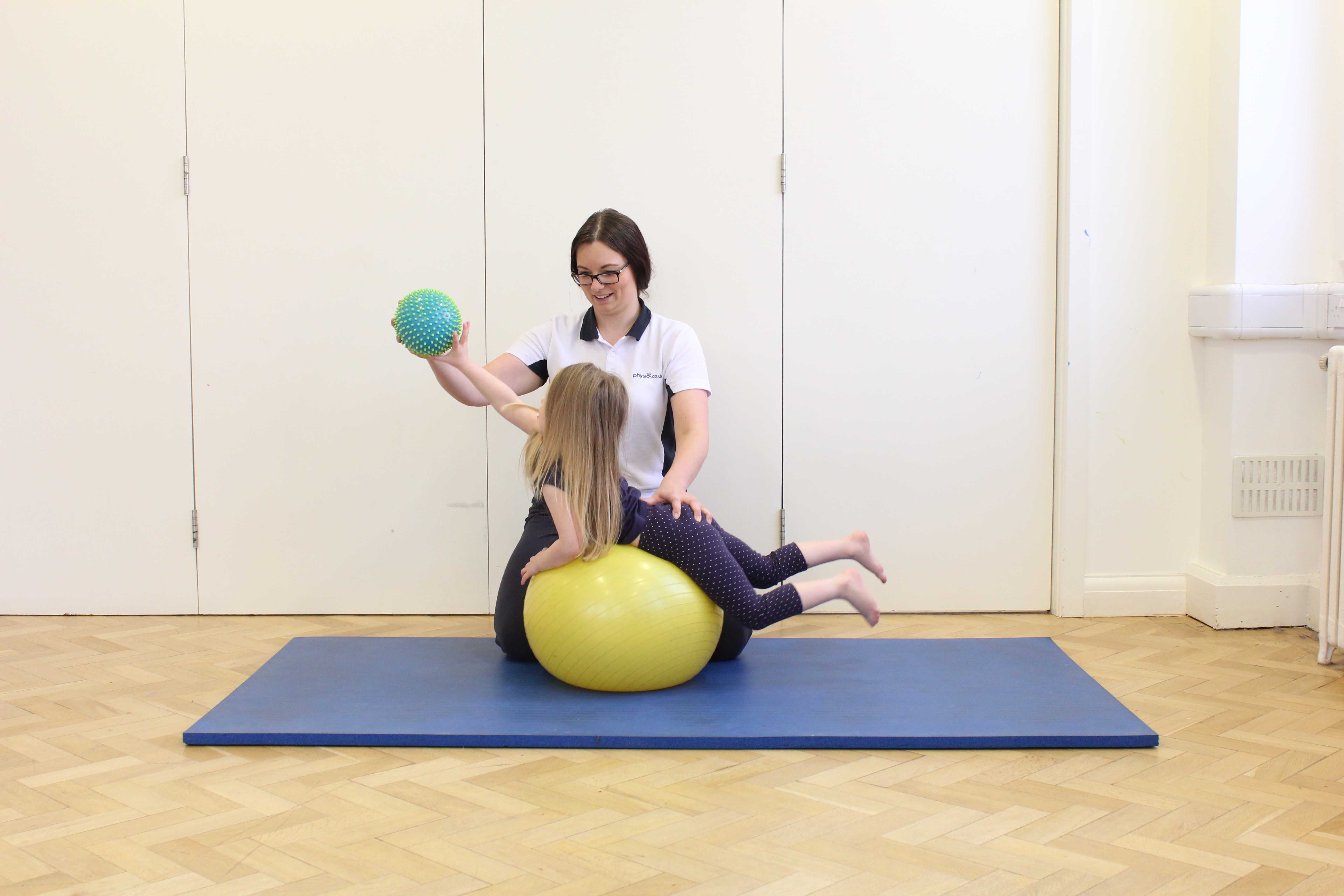 Active stretching exercises over a gym ball under close supervision of specialist paediatric physiotherapist Active stretching exercises over a gym ball under close supervision of specialist paediatric physiotherapist