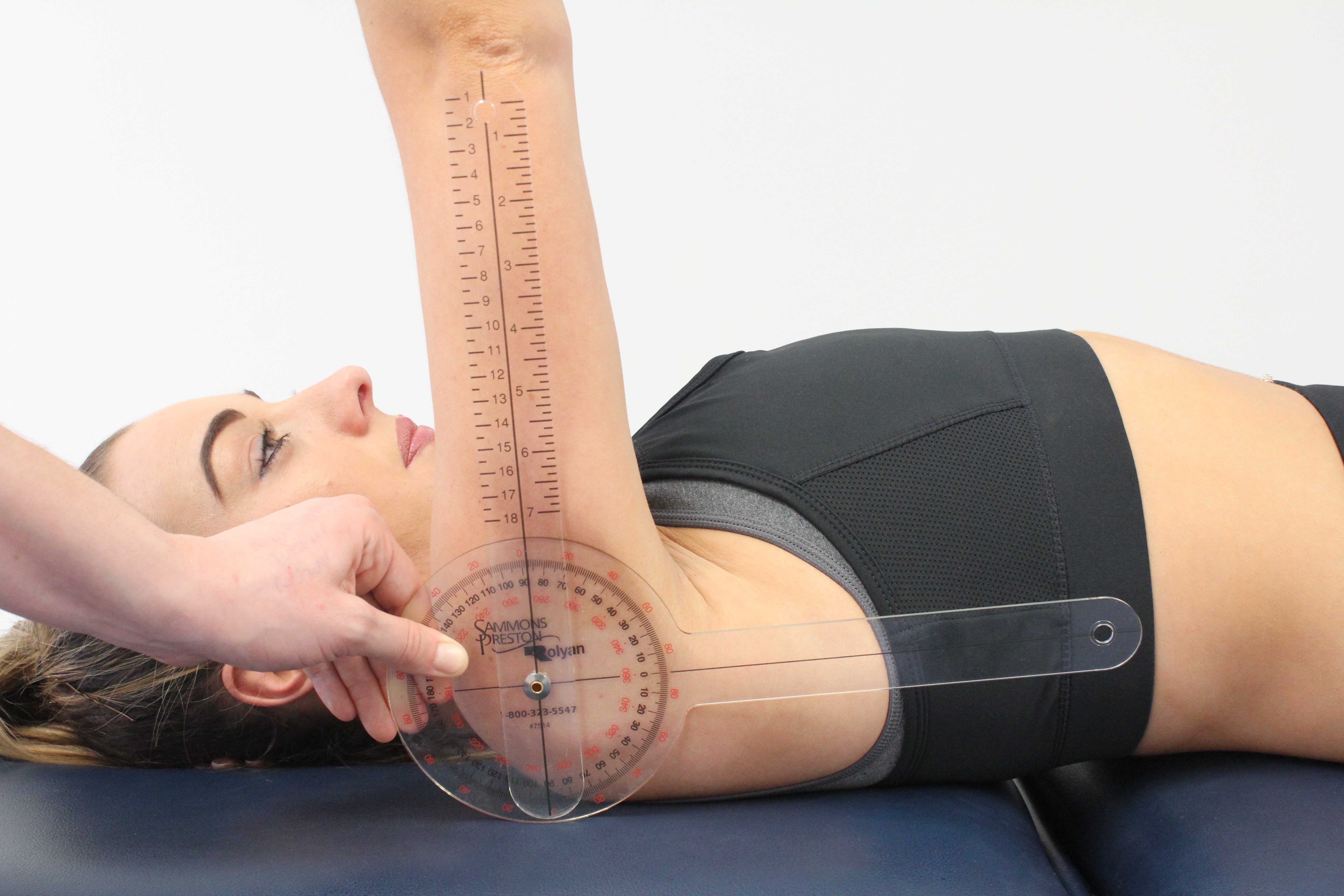 Physiotherapist measuring available range of movement at the shoulder using a goniometer Physiotherapist measuring available range of movement at the shoulder using a goniometer