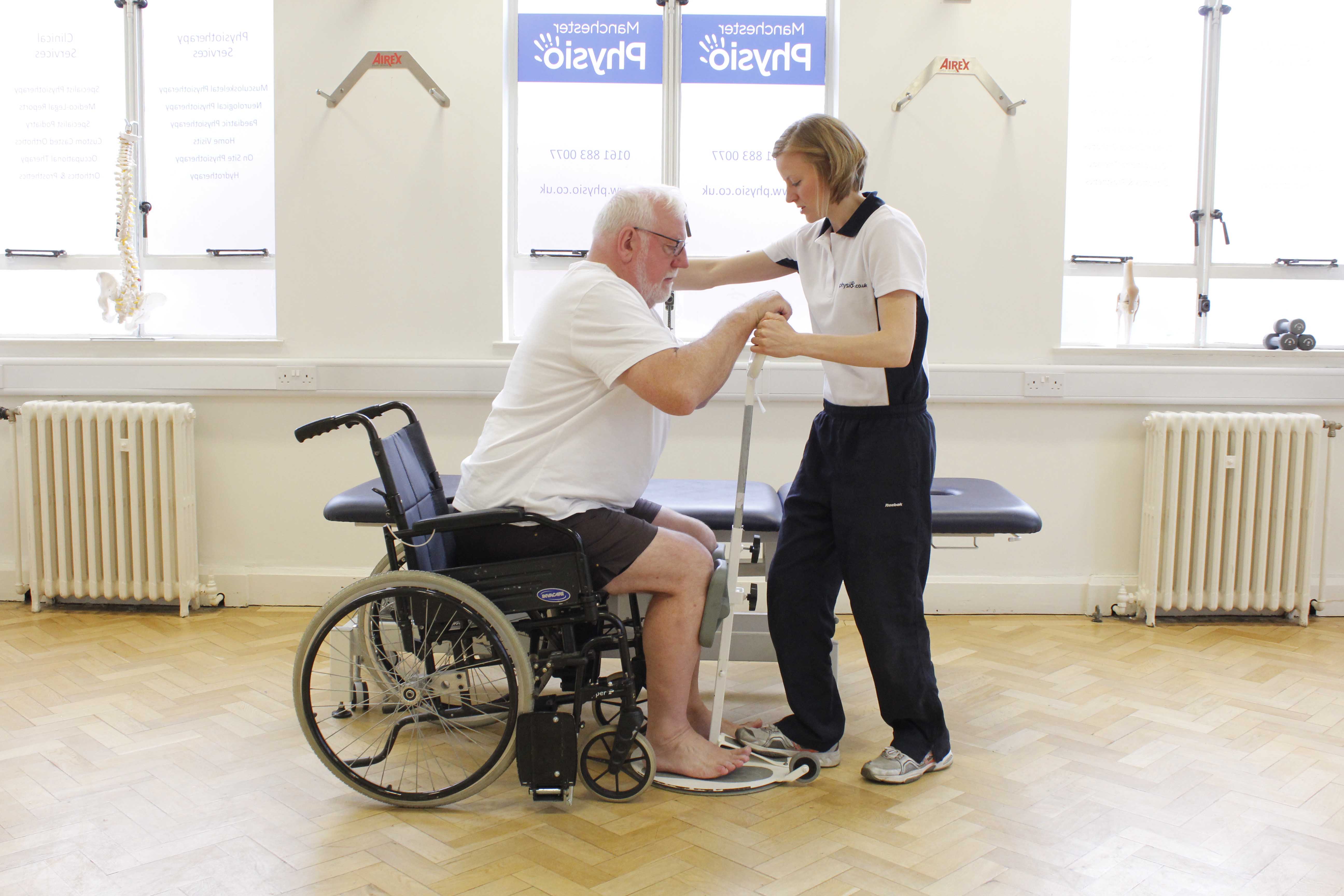 Neurological physiotherapist assisting mobility transfers using a pivot standing frame