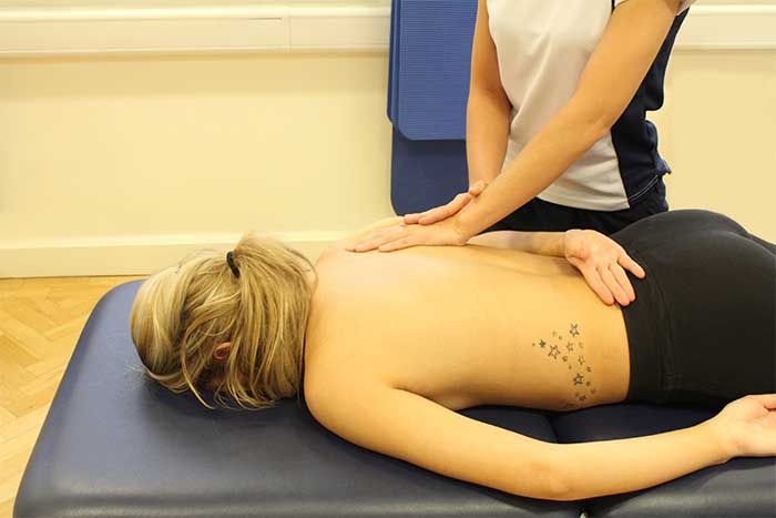 Customer receiving a shoulder massage while in a relaxed position in Manchester Physio Clinic 
