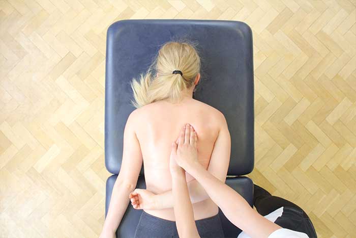 Customer receiving an upper back massage while in a relaxed position in Manchester Physio Clinic