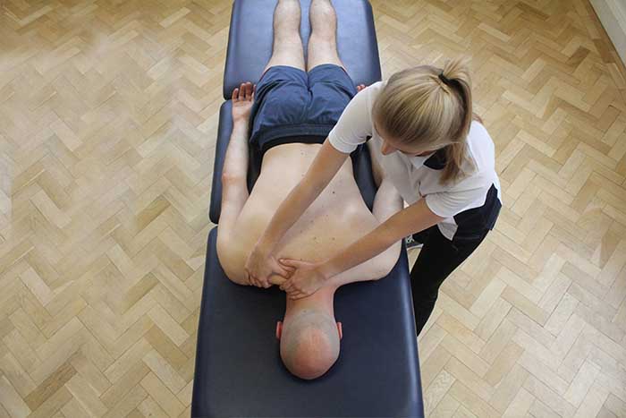 Customer receiving shoulder massage while in a relaxed position in Manchester Physio Clinic