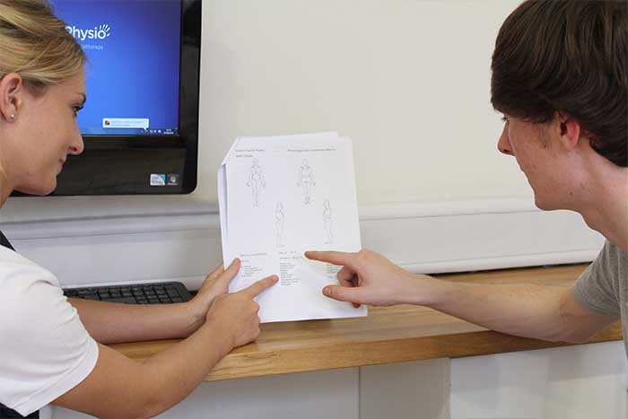 Customer going through a sheet of different body parts with instructor in Manchester Physio Clinic