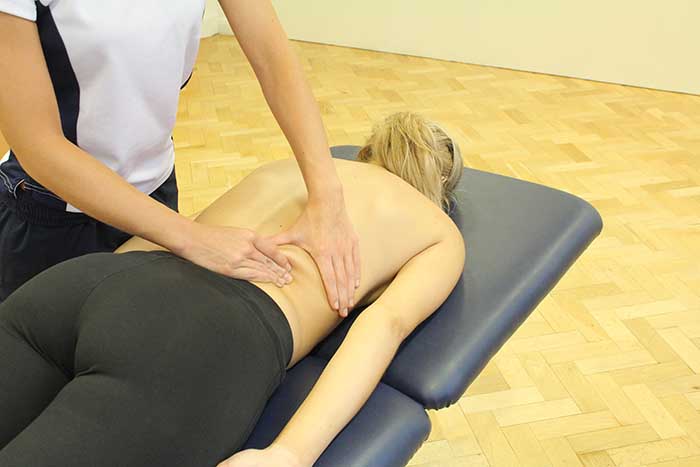 Customer receiving lower back massage in relaxed position in Manchester Physio Clinic