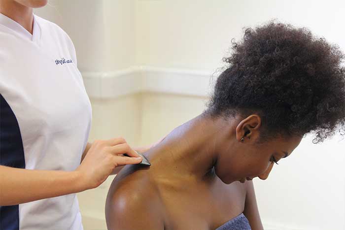 Customer receiving upper shoulder massage using instrument in Manchester Physio Clinic Customer receiving upper shoulder massage using instrument in Manchester Physio Clinic