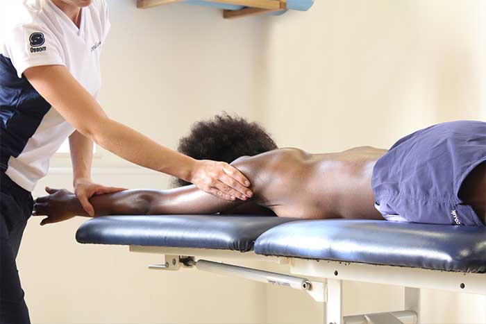 Customer receiving upper arm massage while in a relaxed position in Manchester Physio Clinic