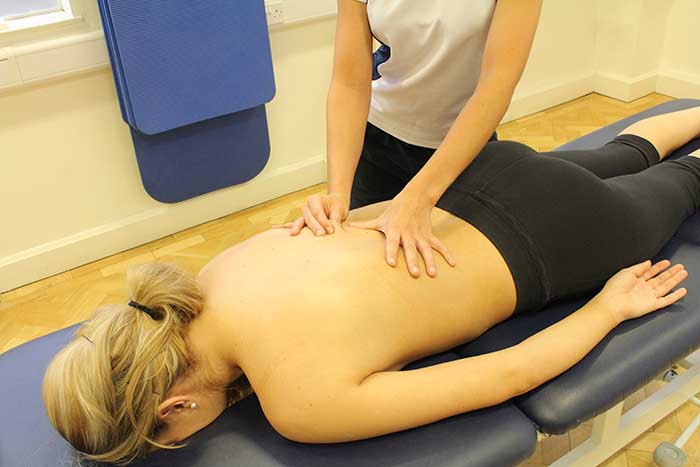 Customer receiving a lower back massage while in a relaxed position in Manchester Physio Clinic