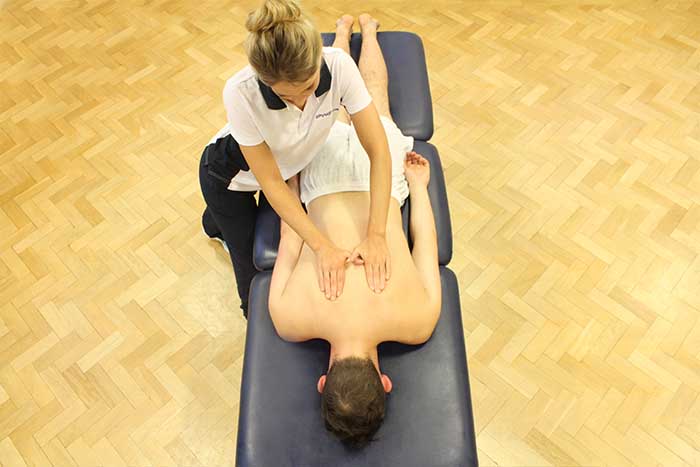 Customer receiving an upper back massage while in a relaxed position in Manchester Physio Clinic