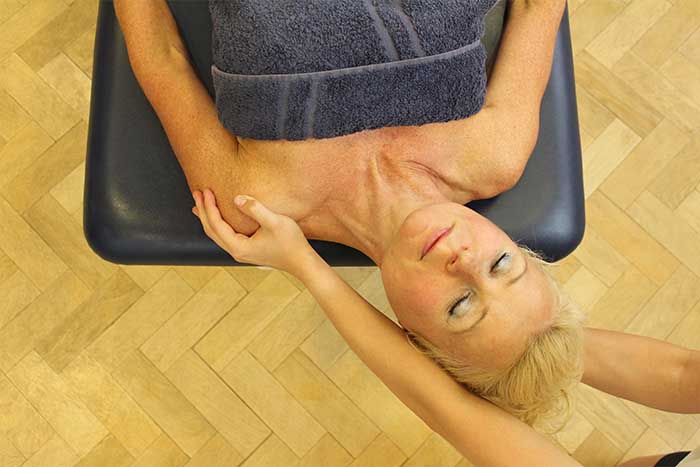 Customer receiving a shoulder massage while in a relaxed position in Manchester Physio Clinic