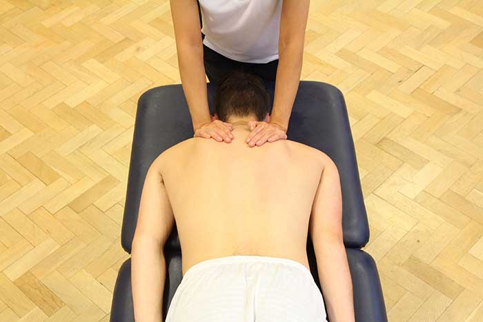 Customer receiving a shoulder massage while in a relaxed position in Manchester Physio Clinic