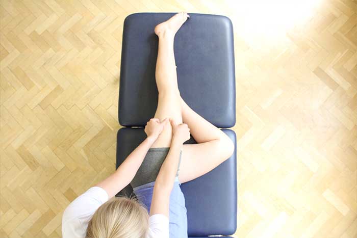 Customer receiving a thigh massage while in a relaxed position in Manchester Physio Clinic