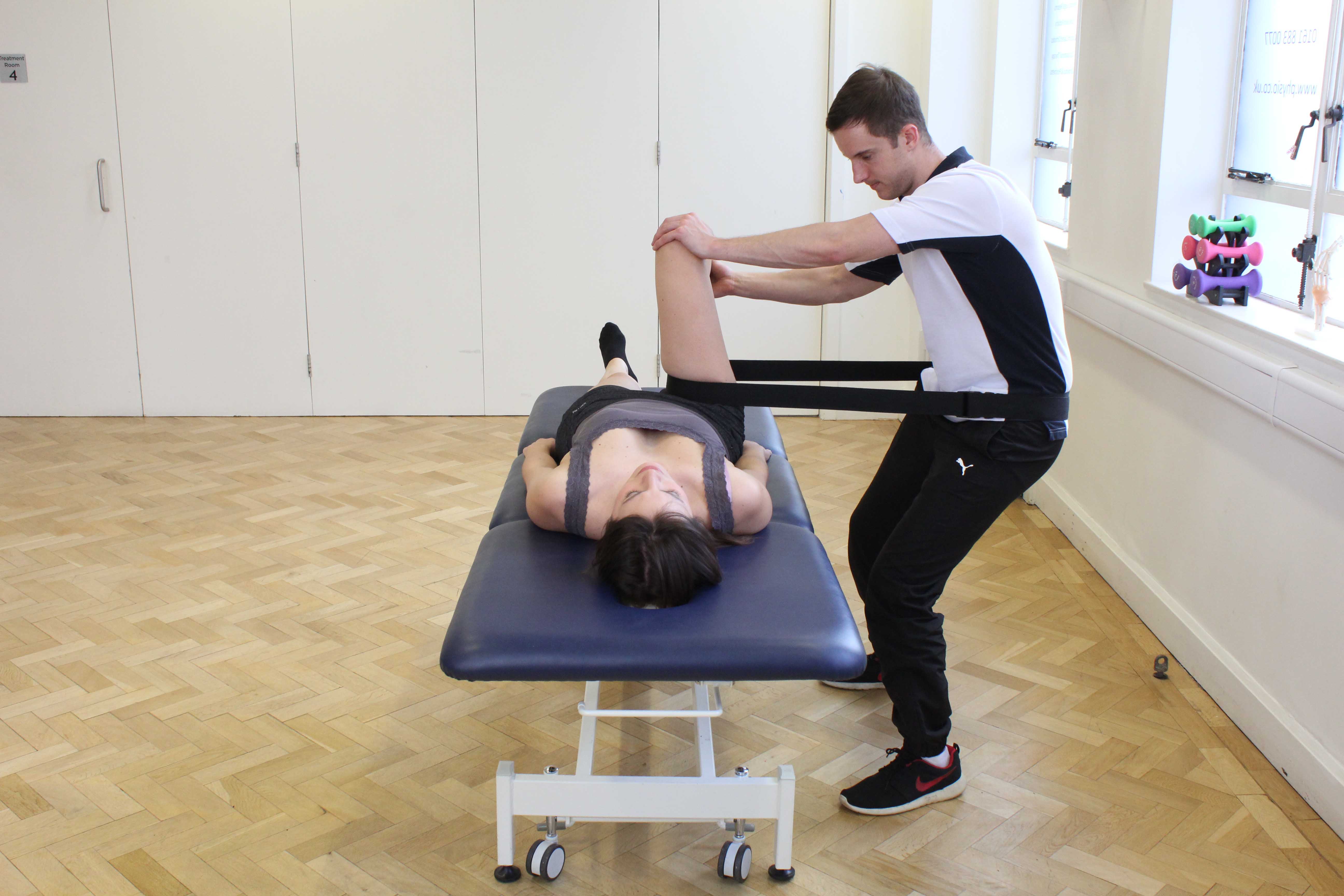 Physiotherapist using a strap to mobilise the hip joint Physiotherapist using a strap to mobilise the hip joint