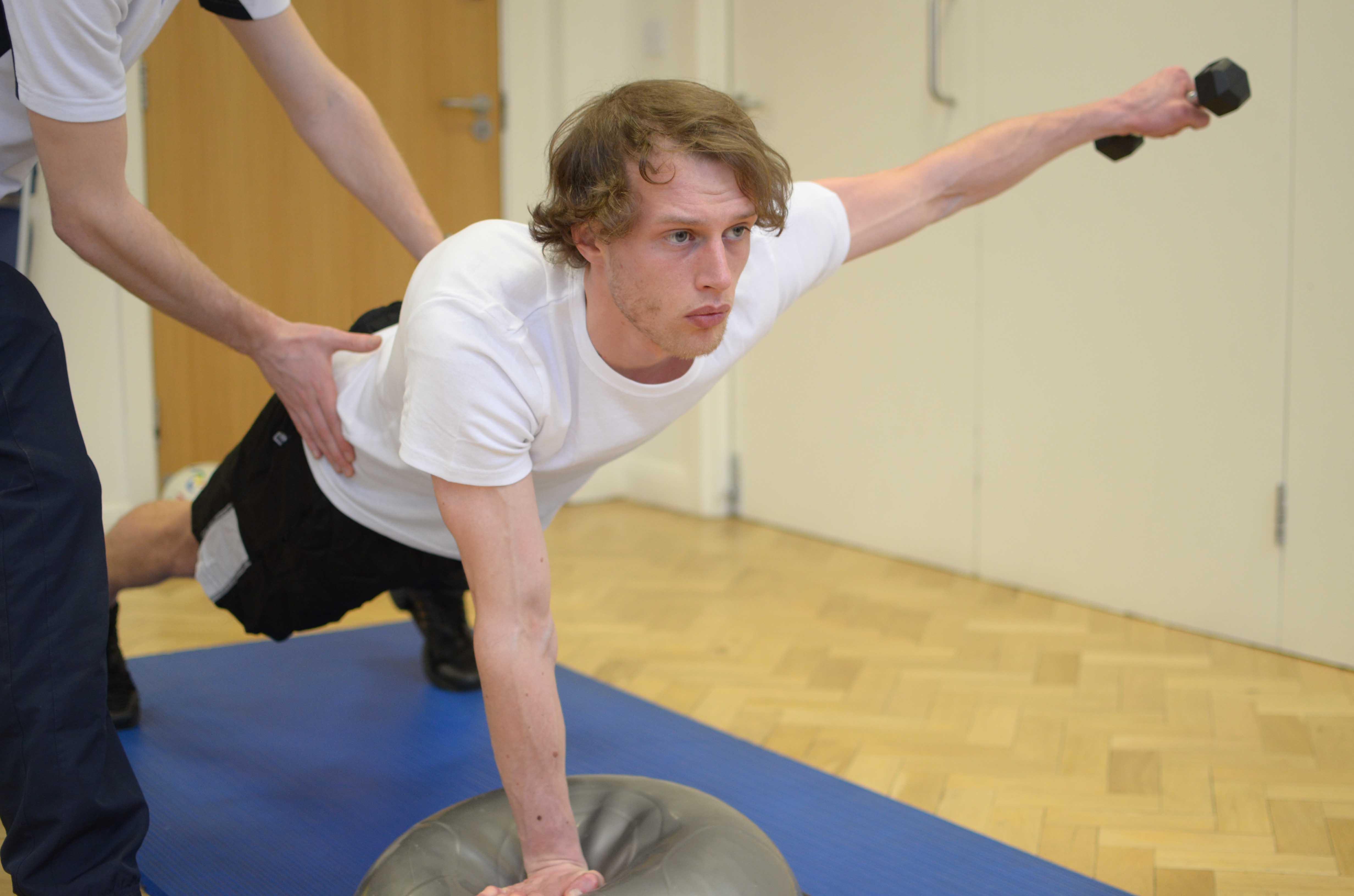 Physiotherapist supervising dumbell fly exercises for the shoulder