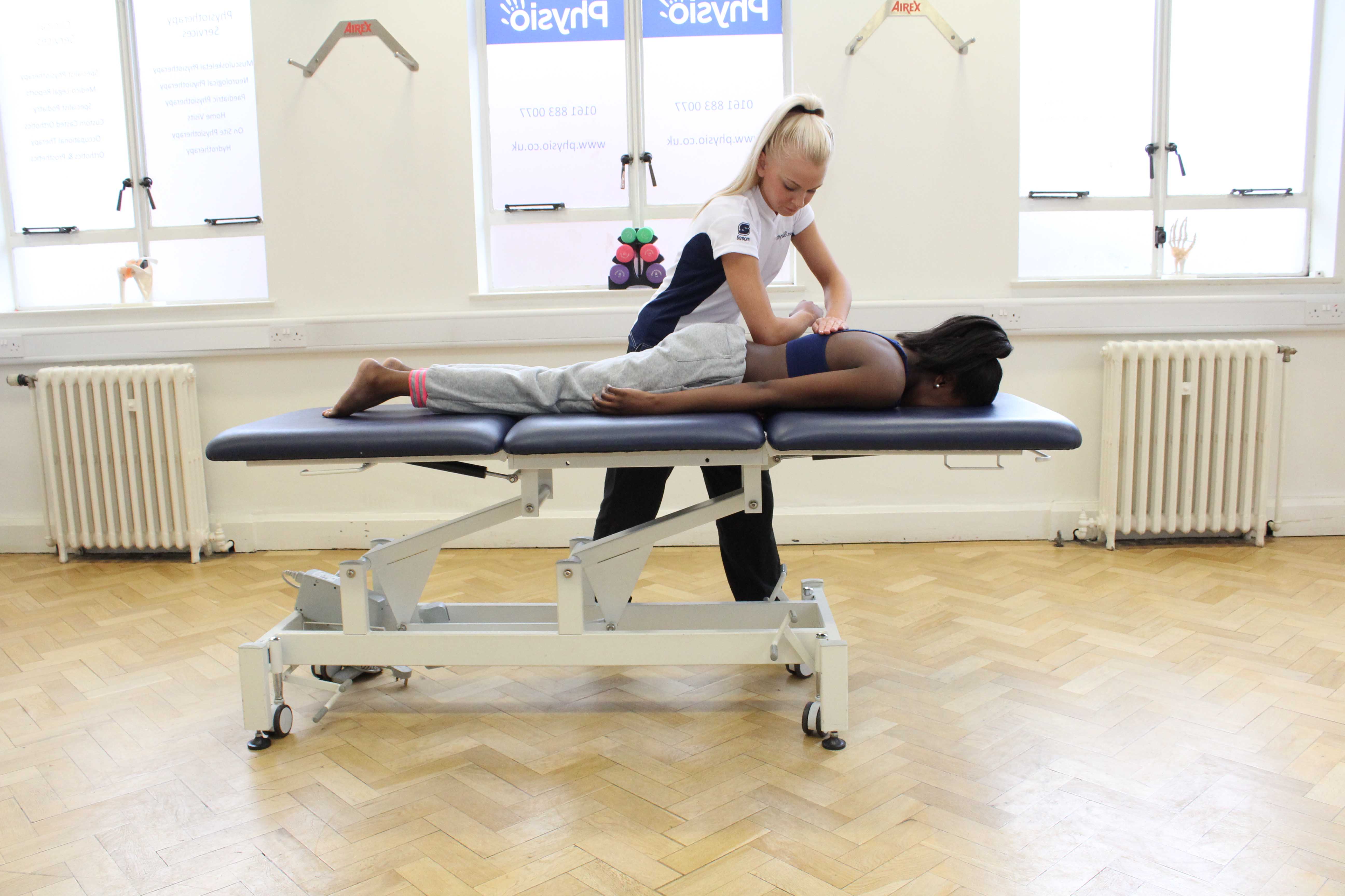 Deep tissue massage to the lumbar region by physiotherapist to lower muscle tone and aching Deep tissue massage to the lumbar region by physiotherapist to lower muscle tone and aching