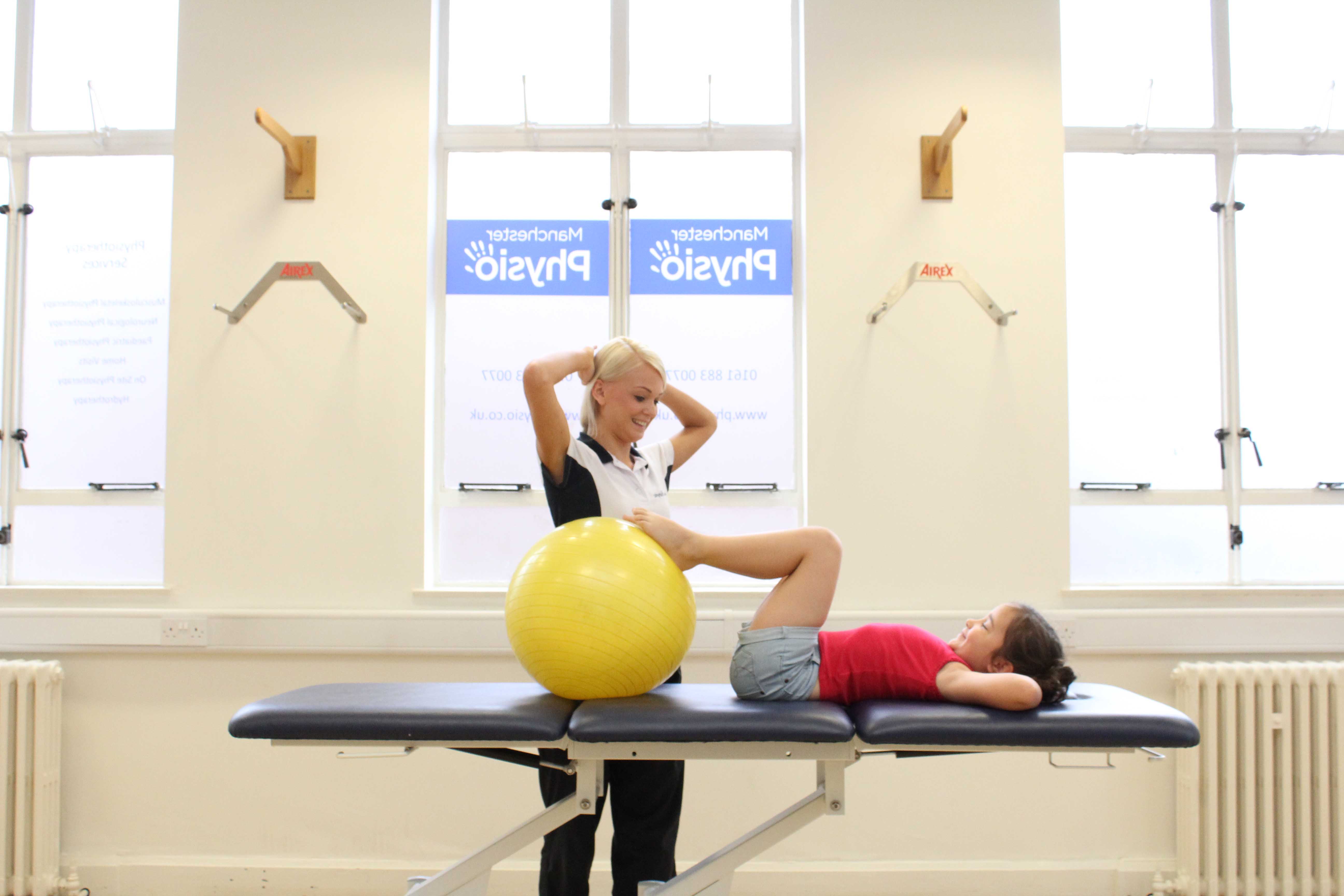 Specialist physiotherapist supervising lower limb stretching exercises using a gym ball Specialist physiotherapist supervising lower limb stretching exercises using a gym ball