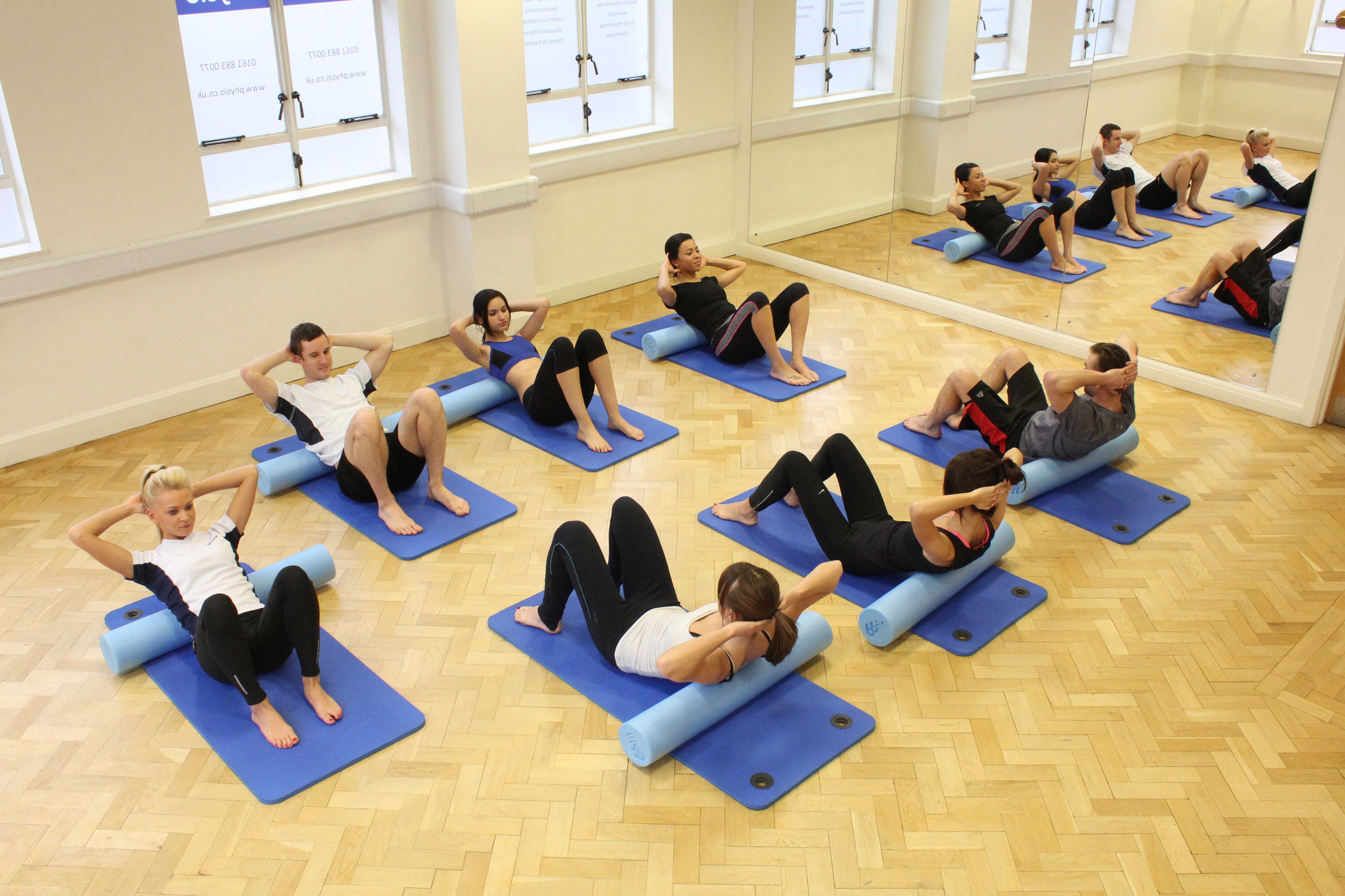 Physiotherapist led pilates class using foam rolls 