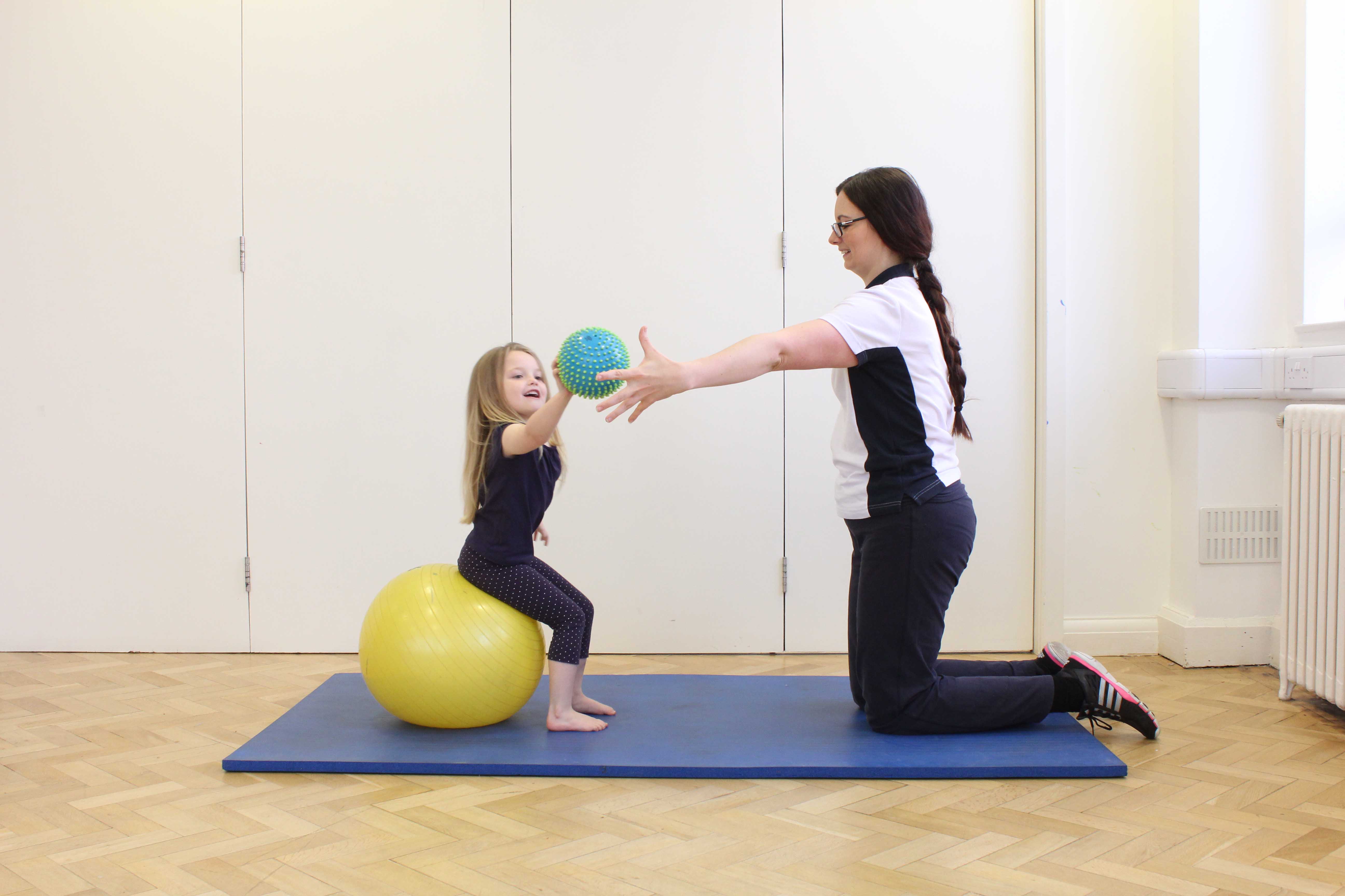 Physiotherapist encouraging increased range of movement with a reaching game. Physiotherapist encouraging increased range of movement with a reaching game.