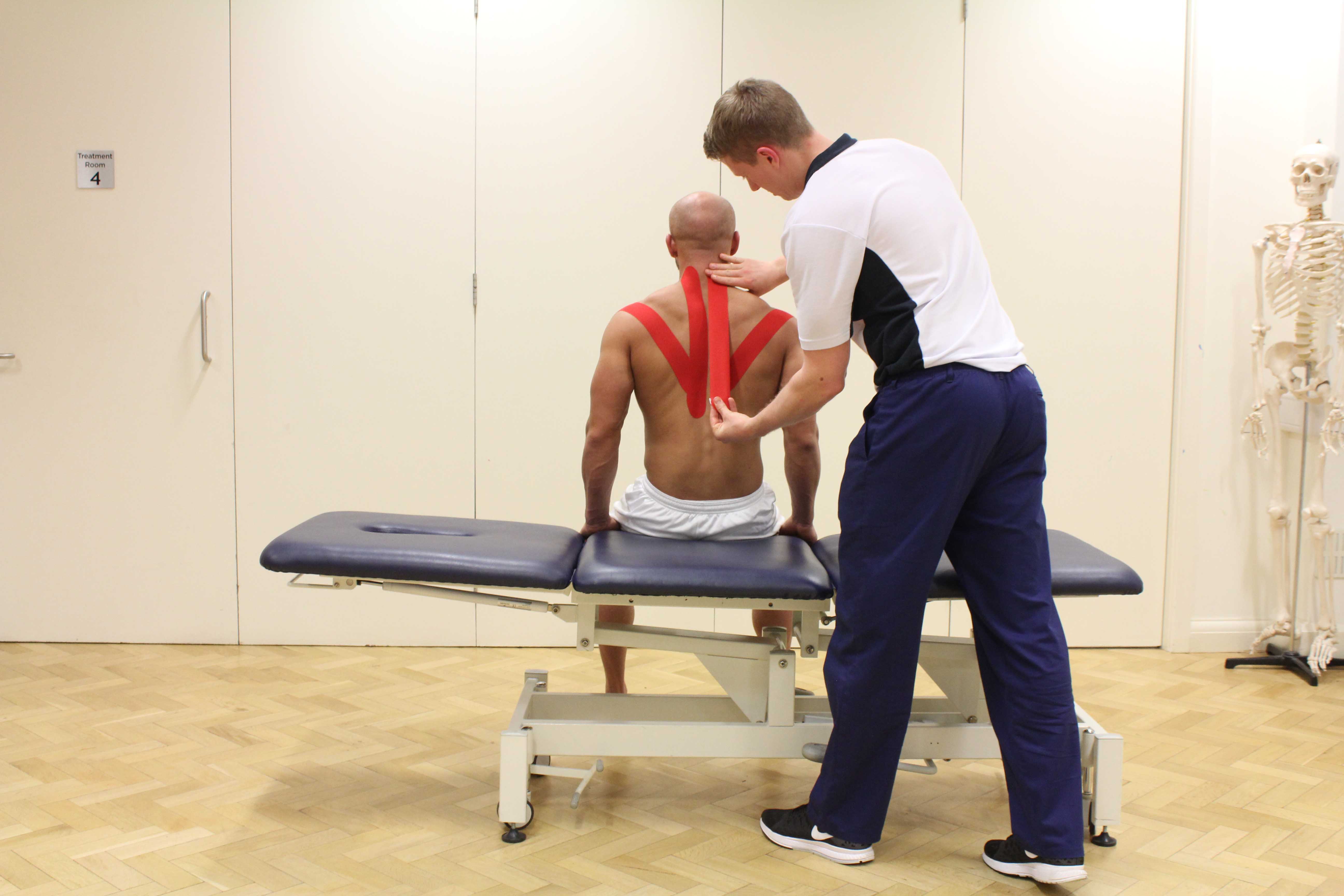 Experienced Physiotherapist using specialist tape to support and stabilise movement across the shoulders Experienced Physiotherapist using specialist tape to support and stabilise movement across the shoulders
