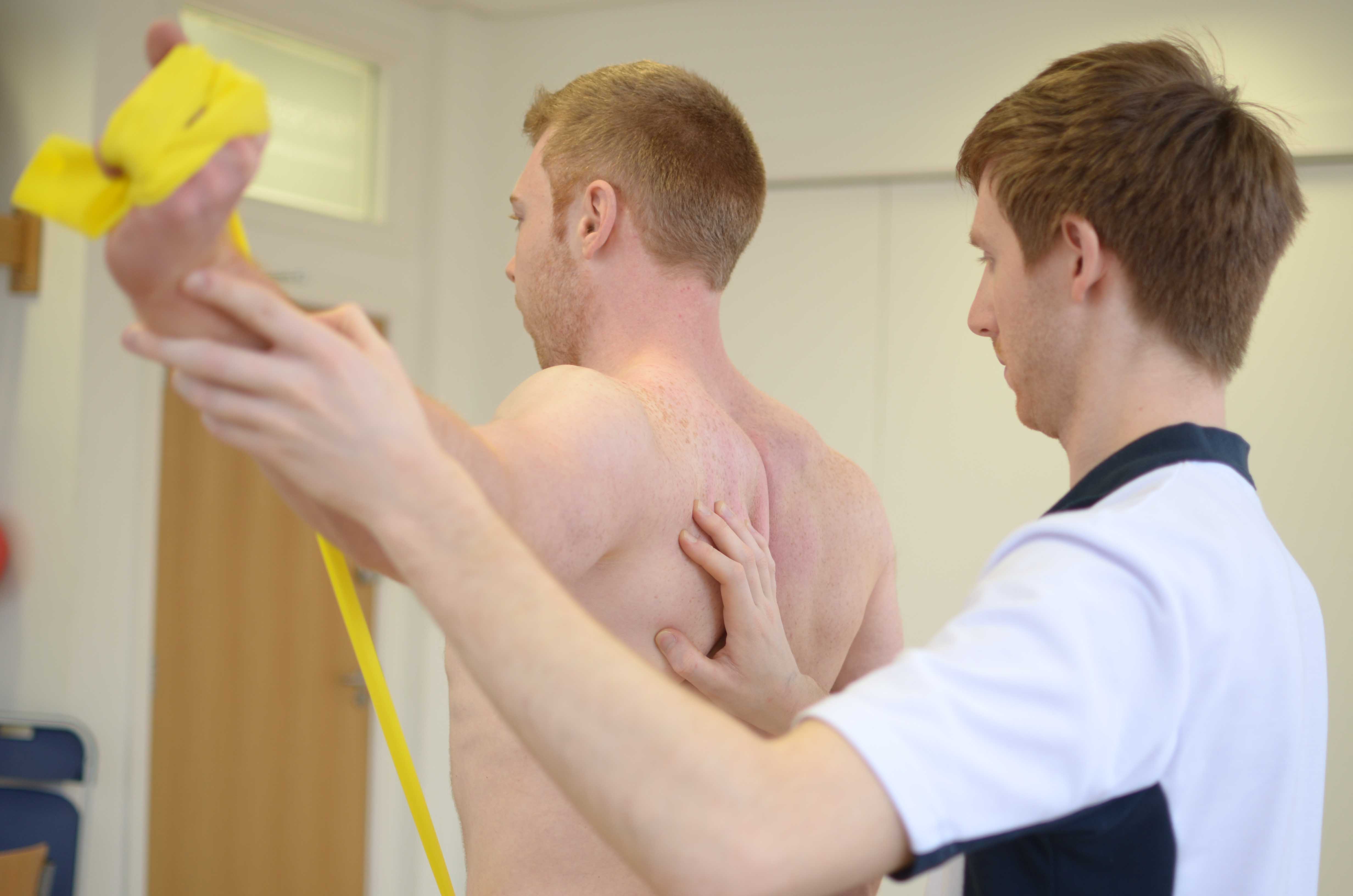 Physiotherapist supervising scapula setting exercises Physiotherapist supervising scapula setting exercises